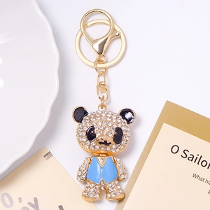 Detail view of a bear keychain with sky blue enamel vest and sparkling white rhinestones