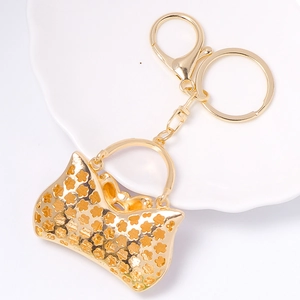 Golden handbag keychain accessory with hollow floral patterns and lobster clasp