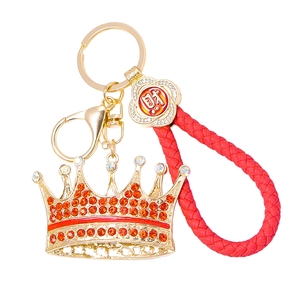 Detail of crown keychain with red rhinestones, braided cord, and lucky charm