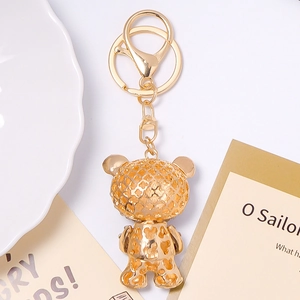 Golden bear keychain with heart pattern and rhinestone details on a white surface
