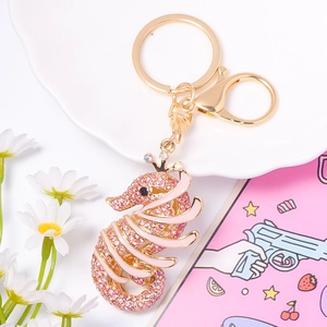 Détail du porte-clés hippocampe avec strass roses et émail blanc sur assiette blanche