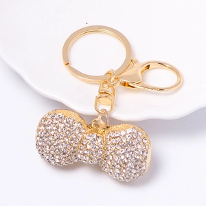 Macro shot of gold bow keychain featuring pavé rhinestones on a white ceramic plate