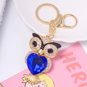 Gros plan détaillé du porte-clés hibou doré avec cristal de cœur bleu et strass