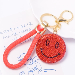 Dettaglio portachiavi con faccina sorridente in strass rossi, cordino e moschettone dorato