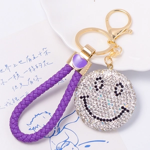 Dettaglio del portachiavi in pelle intrecciata viola con ciondolo smiley di strass