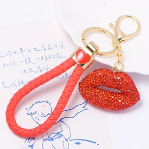 Detail of red rhinestone lips keychain with braided leather rope and gold hardware