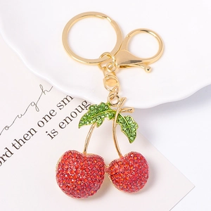 Gros plan des strass en cristal rouge et vert sur le porte-clés cerise en métal doré