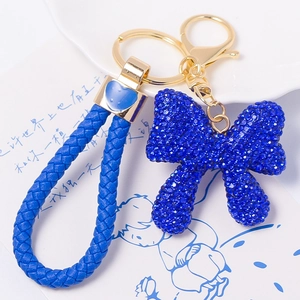 Detailed close-up of blue rhinestone bow keychain with braided leather rope strap