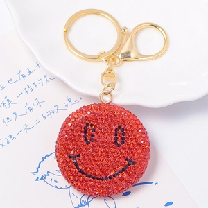 Dettaglio del portachiavi con faccina sorridente in strass rossi e chiusura dorata