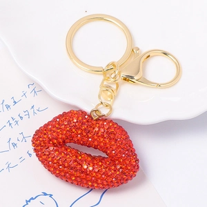 Sparkling red rhinestone lip keychain with golden ring and lobster clasp on a white plate