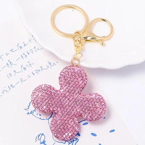 Detailed view of pink rhinestone four-leaf clover keychain with gold metal ring and clasp