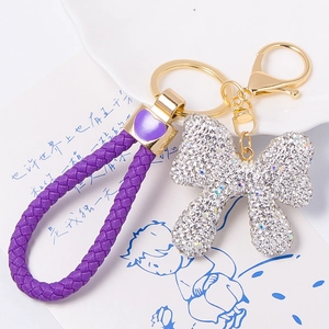 Close-up of purple braided rope keychain with sparkling rhinestone bow and gold-plated hardware