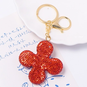Sparkling red four-leaf clover keychain with golden metal ring and lobster clasp