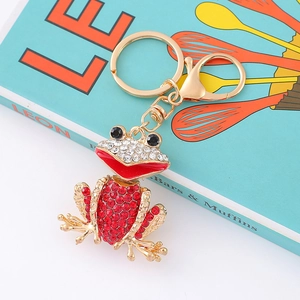 Macro detail of frog keychain showing red crystal embellishments and golden metal base