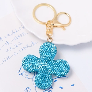 Macro detail of blue textured clover keychain with golden metallic ring and clasp
