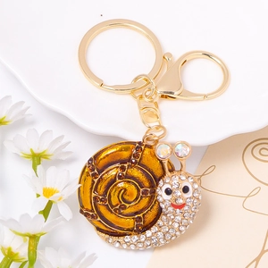 Close-up of golden snail keychain with brown enamel, rhinestones and lobster clasp