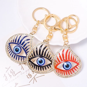 Three gold evil eye keychains with blue, black, and red crystal teardrop designs