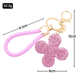 Pink rhinestone four-leaf clover keychain with woven leather strap and gold metal clasp