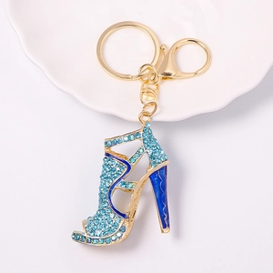 Macro shot of blue rhinestone high heel keychain with gold metal buckle on white plate