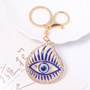 Detailed macro shot of a golden Evil Eye keychain with blue enamel and white rhinestones