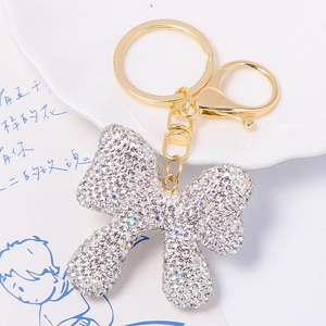 Detail of golden bow keychain with sparkling rhinestones and lobster clasp on white tray