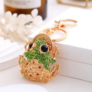Golden feng shui money frog keychain with green rhinestones and lucky coins on white display