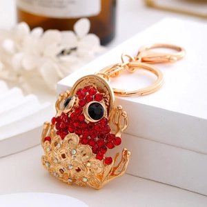 Detail of golden frog keychain with sparkling red rhinestones and ancient coin base