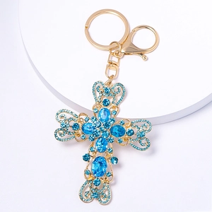 Vue détaillée du porte-clés croix dorée serti de strass bleus avec son fermoir mousqueton