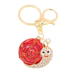 Golden snail keychain with red enamel and rhinestones on a white background