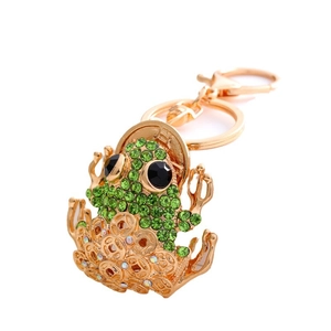 Golden frog keychain with green rhinestones and ancient coin charms on white background