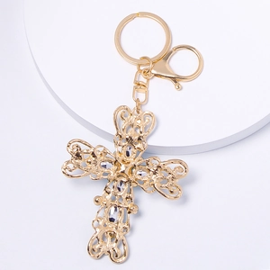 Porte-clés croix filigrane dorée avec strass sur présentoir circulaire blanc