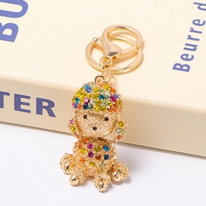 Golden poodle keychain with colorful rhinestones leaning on a white box gift setup