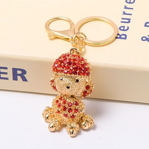 Close-up of golden poodle keychain featuring sparkling red and gold rhinestones on a book