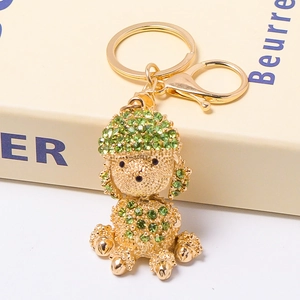 Close-up of golden poodle keychain with green rhinestones on book surface