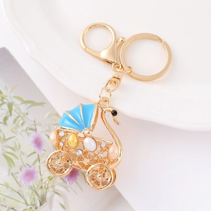 Detail of a swan-themed stroller keychain with blue enamel, rhinestones, and pearls