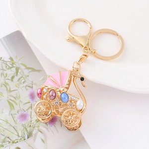 Detailed view of baby stroller keychain with colorful stones and pink enamel finish