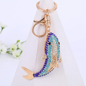 Détail d'un porte-clés poisson doré avec des strass étincelants bleus et blancs