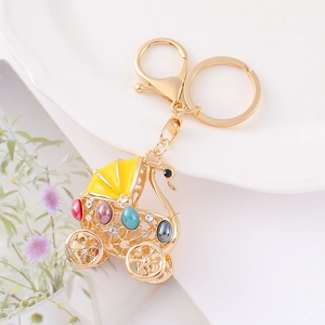 Elegant golden carriage keychain with colorful gemstones on a white porcelain plate