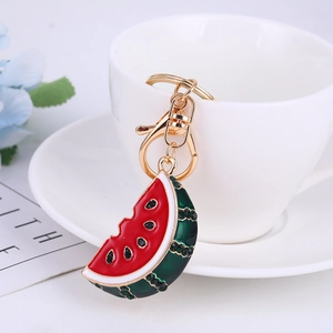 Close-up of watermelon keychain with red enamel and sparkling crystal accents on white cup