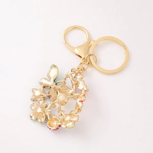 Porte-clés couronne de fleurs dorées avec strass roses et verts sur fond blanc