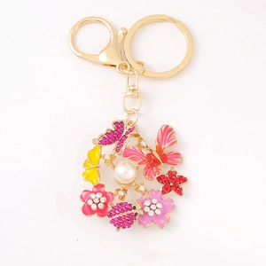 Porte-clés en métal avec papillons, fleurs, strass brillants et détail de perle blanche