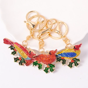 Close-up of bird keychains with colorful rhinestones and holly leaves on a ceramic plate