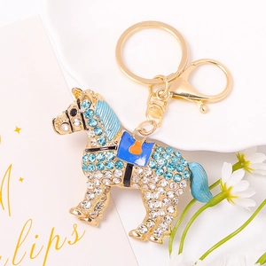 Dettaglio portachiavi a forma di cavallo con strass blu su sfondo di ceramica bianca