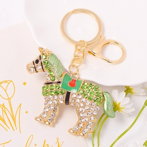 Dettaglio del portachiavi cavallo verde con cristalli su un piatto di ceramica bianca