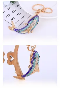 Close-up of blue crystal shark keychain with golden alloy base and sparkling rhinestones