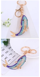 Detail of shark keychain with blue rhinestones and gold lobster clasp on white background