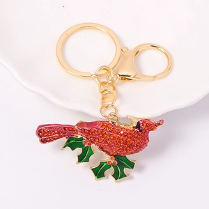 Close-up of a bird keychain with red rhinestones and green holly leaf details