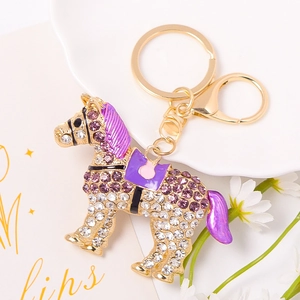 Dettaglio del portachiavi a cavallo con strass viola e moschettone dorato su vassoio