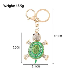 Golden sea turtle keychain with green rhinestones and dimensions shown on white backdrop
