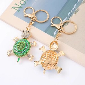 Detailed view of turtle keychain with green crystals and golden metal hollow pattern